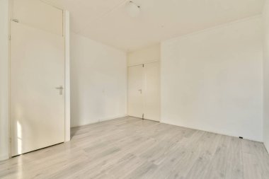 Beyaz duvarları ve basit ahşap döşemeleri olan parlak ve havadar boş bir oda, temiz ve ferah bir hava sağlıyor, iç mimari fikirler için mükemmel..