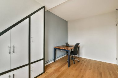 Minimalist bir masa, ergonomik sandalye ve üretkenliği ve konforu artıran çağdaş dolap şiirinin yer aldığı şık bir ofis..