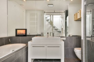 Zarif bir küvet, çift lavabo ve bol doğal ışık içeren minimalist bir tasarım içeren modern bir banyo lüks bir ortam yaratıyor..