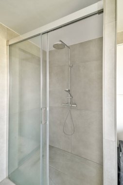 Pürüzsüz cam kapılar ve minimalist tasarım elementlerinin yer aldığı parlak ve çağdaş bir duş alanı. Tarafsız renkler açıklık duygusunu arttırır..