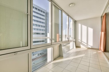 Parlak, havadar, geniş cam pencereli, bol doğal ışığı davet eden, dinlenmek için sakin ve davetkar bir atmosfer yaratan bir yer..