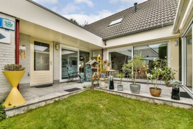 Güzel manikürlü çimenler, saksı bitkileri ve modern mimari elementlerin bulunduğu şık bir açık hava alanı, huzurlu bir yaşam ortamı yaratıyor..