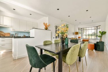 Şık bir masa, renkli sandalyeler ve zarif bir dekor içeren modern bir yemek salonu. Parlak bir atmosferin ortasında toplanmak ve misafirleri eğlendirmek için mükemmel..