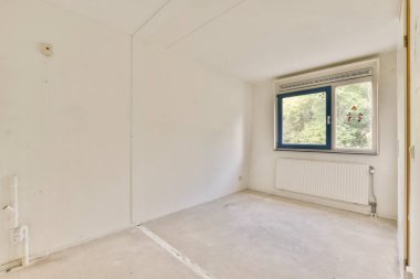 Geniş pencereli, doğal ışığın içeri girmesini sağlayan boş bir oda. Minimalist tasarım, açıklık ve potansiyel hissine katkıda bulunur..