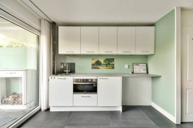 Minimalist tasarımı olan, yeşil duvarları ve fonksiyonel bir düzeni olan şık, modern bir mutfak. Modern evler ve şık iç mekanlar için mükemmel..