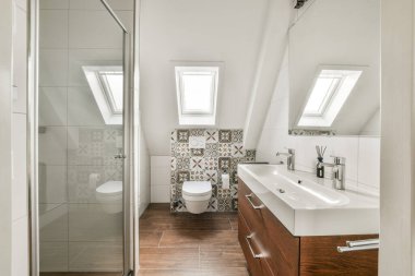 Duş, dekoratif fayanslar ve parlak ve davetkar bir atmosfer yaratan bol miktarda doğal ışık içeren gösterişli ve modern bir banyo..
