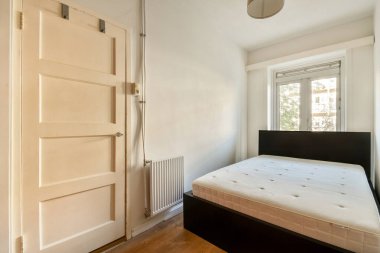 Parlak ve havadar minimalist bir yatak odası. Beyaz bir duvara yaslanmış basit bir yatak odası. Doğal ışığı uzaya davet eden bir pencereyle tamamlanmış..