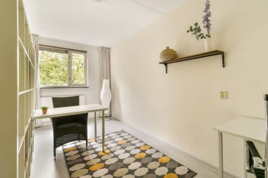 Masa, sandalye ve bitki gibi dekoratif elementlerin yer aldığı parlak, minimalist bir çalışma alanı. Doğal ışık, üretkenlik için ideal olan davetkar atmosferi arttırır..