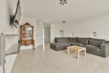 Gri bir kanepe, minimalist bir dekor, açık renkli duvarlar ve şık ışıklandırma, rahatlama ve sosyalleşme için mükemmel bir oturma odası..