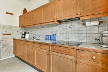 Ahşap dolaplar, döşeme döşemeleri ve işlevsellik ve estetik için tasarlanmış rahat aletlerle donatılmış modern bir mutfak..