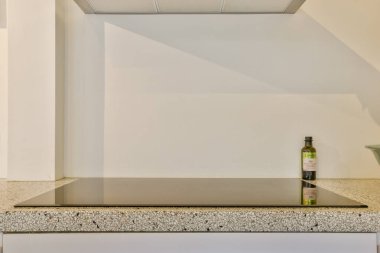 Şık, minimalist mutfak tezgahı, modern bir tasarım, taş kaplama ve en küçük aletler. Ayarlamada temiz çizgiler ve işlevsellik vurgulanıyor.