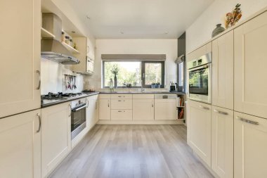 Parlak ve havadar modern mutfak, gösterişli dolaplar, çağdaş cihazlar, ve geniş pencereler, doğal ışığın mekanı aydınlatmasına olanak sağlıyor..