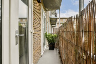 İçinde saksı bitkisi ve ahşap bir çit olan modern bir balkon. Gösterişli tasarım, çağdaş mimariyi ve açık havada yaşamı ön plana çıkarıyor..