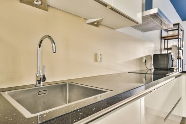 Modern bir mutfak, şık bir lavabo ve minimalist tasarım elementleri içeriyor, fonksiyonel ve estetik bir yemek alanı yaratıyor..
