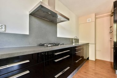 Karanlık dolapları ve modern aletleri olan, aşçılık meraklıları için mükemmel minimalist bir tasarımı sergileyen çağdaş bir mutfak..