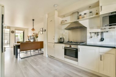 Gösterişli bir mutfak, paslanmaz çelik eşyalar ve yakındaki pencerelerden gelen doğal ışıkla aydınlatılmış iyi organize edilmiş bir yapı..