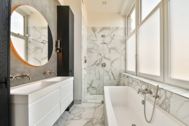Zarif demirbaşlı modern bir banyo, mermer yüzeyler, ve büyük bir ayna, mükemmel dengeleyici zarafet ve işlevsellik.