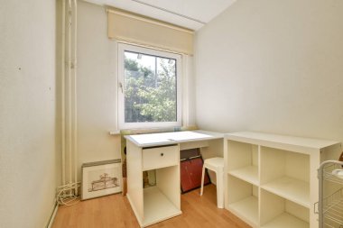 Basit bir masa, kitaplıklar ve pencereden gelen doğal ışığın yer aldığı parlak, minimalist bir ofis. Çalışmak ya da uzak çalışma için ideal.