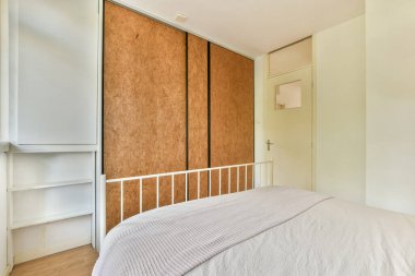 Huzurlu ve modern bir yatak odası. Minimalist bir tarzı var. Rahat bir yatağı, ahşap döşemesi ve parlak bir deposu var. Yumuşak renk paleti sükuneti arttırır.