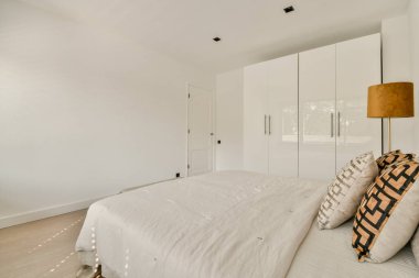 Tarafsız tonlara, minimalist mobilyalara ve rahat bir atmosfer yaratan bol miktarda doğal ışığa sahip sakin ve şık bir modern yatak odası..