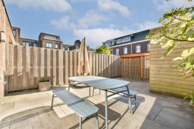 Güneşlenmek ve dinlenmek için mükemmel, ahşap bir çite dayalı masa ve bank içeren parlak ve davetkar bir veranda..