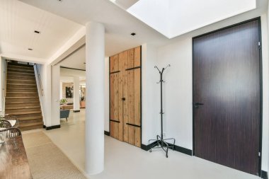 Merdiven, ahşap kapılar ve doğal ışığa vurgu yapan, davetkar bir atmosfer yaratan güzel tasarlanmış modern bir iç mekan..