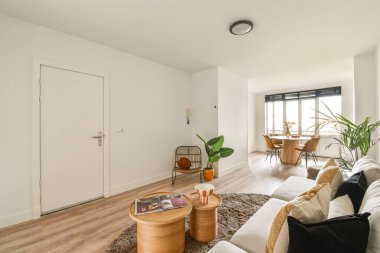 Minimalist tasarımın, ahşap aksanların ve doğal ışığı davet eden geniş pencerelerin yer aldığı çağdaş bir yaşam alanı davetkar bir atmosfer yaratıyor..