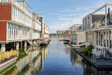 Modern evler, mimari ve doğanın bir karışımını yansıtan sakin bir su yolu oluşturur. Kanal boyunca demirlemiş tekneler, manzarayı güzelleştiriyor..