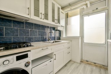 Modern bir mutfak, şık mavi fayanslar, parlak aletler, ve geniş depolama alanı, fonksiyonel bir yemek ortamı için mükemmel..