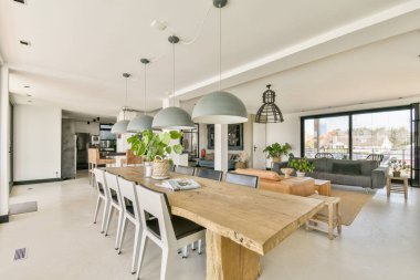 Geniş bir yemek alanı, çağdaş mobilyalar ve doğal ışığa izin veren geniş pencereleri olan şık bir iç mekan..