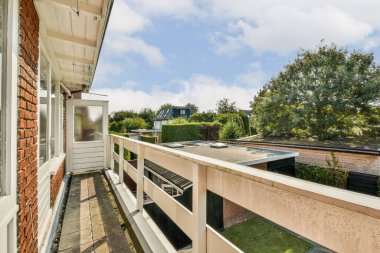 Parlak yeşilliğe tepeden bakan manzaralı bir balkon, uzaktaki modern mimariye bir bakış ile huzurlu bir kaçış sunuyor..