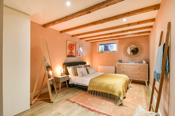 This modern bedroom features warm tones, wooden beams, and stylish decor, creating a cozy and inviting atmosphere for relaxation.