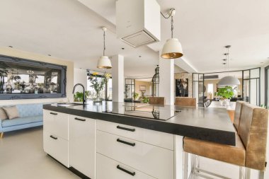 Çağdaş bir mutfak tasarımı gösterişli dolaplar, modern aletler ve zarif aydınlatma armatürleri içeriyor. Parlak ve davetkar bir yemek alanı yaratıyor..