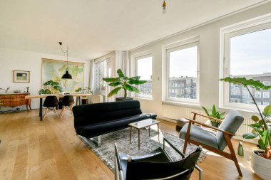 Geniş bir oturma odası şık siyah bir kanepe, büyük pencereler, eski bir harita ve çağdaş mobilyalar, rahatlatıcı ve davetkar bir atmosfer yaratıyor..