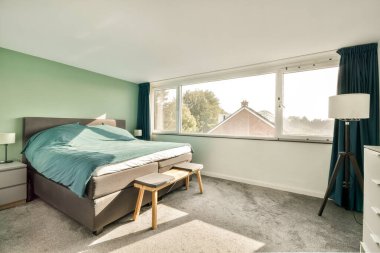 Huzurlu ve şık bir yatak odası rahat bir yatak odası, yumuşak tekstil ve büyük pencereler doğal ışığı davet ederek rahatlatıcı bir atmosfer yaratıyor..