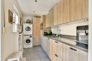 Ahşap dolap, entegre cihazlar ve işlevsel bir yemek alanı yaratan minimalist bir düzen içeren gösterişli mutfak tasarımı..