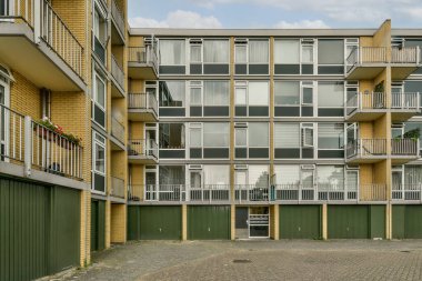 Çok sayıda balkon ve geniş pencereli çağdaş bir konut yapısı, temiz hatları ve modern estetiğiyle vurgulanıyor. Avlu cazibesini arttırıyor..
