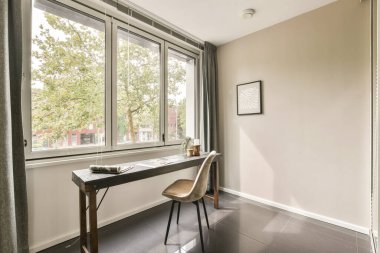 Geniş pencereli bir masa ve sandalyeye sahip parlak, minimalist ev ofisi, taze yeşillik manzaralı verimliliği artırıyor..