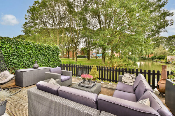 Благоустроенная открытая гостиная, окруженная пышной зеленью и с видом на мирную воду, идеально подходит для отдыха и развлечений.