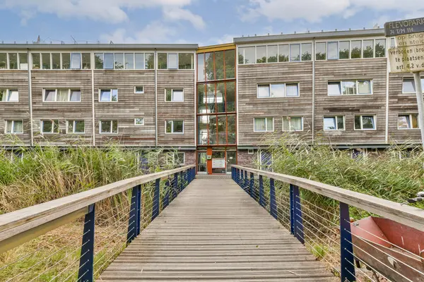 Çağdaş ahşap bir yapı. Etrafı yeşilliklerle çevrili. Birden fazla pencere ve girişe açılan bir yürüyüş yolu var..