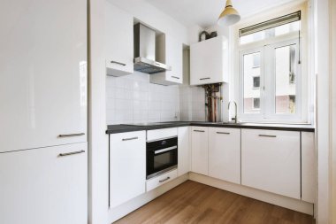 Beyaz duvarları olan modern mutfak, lavabosu ve ocağı olan modern tezgahlar..