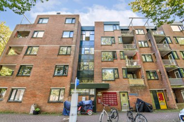 Geniş pencereli birçok katlı çağdaş bir apartman. Bisikletler dışarıda park edilmiş, şehir yaşam tarzına yeni bir hava katıyor..