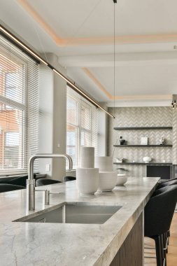 Çağdaş ışıklandırması, zarif mobilyaları ve minimalist estetiği olan şık ve şık bir mutfak. Tasarım işlevsellik ve güzelliğin uyumlu bir karışımını sergiliyor..