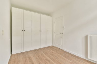 Açık renkli duvarları ve doğal ahşap döşemeleri olan, minimalist estetiği geliştiren parlak, modern bir iç mekan..