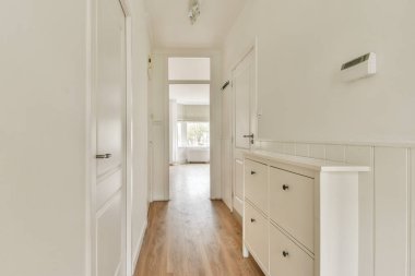 Geniş, aydınlık bir koridor, temiz hatlar ve minimalist bir tasarım, açık renkli duvarlar ve modern estetik için ahşap döşemeler..