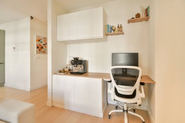 Zarif bir masa, ergonomik sandalye ve parlak, minimalist bir çevrede üretkenliği artıran kahve makinesi içeren şık ve modern bir ofis..