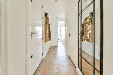 Gösterişli tasarım, ahşap döşeme ve hoş bir atmosfer yaratan dekoratif rafların bulunduğu çağdaş bir koridor. Doğal ışık alanı genişletir..