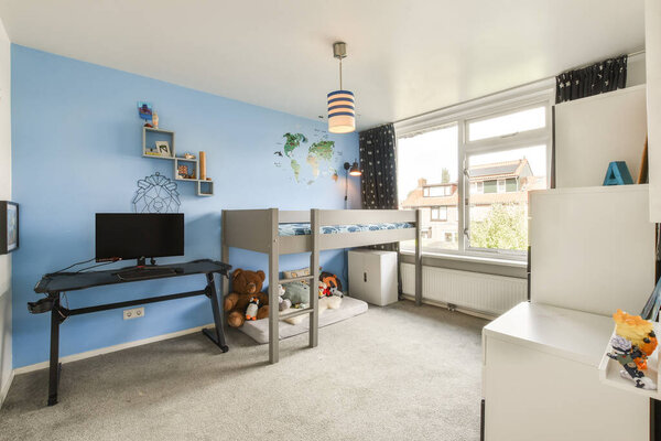 Стильная детская спальня с двухъярусной кроватью, голубыми стенами и уютной игровой зоной. Номер включает в себя мебель и украшения, которые создают привлекательную атмосферу.
