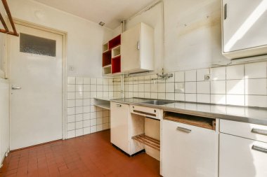 Beyaz fayansların ve minimalist dolapların olduğu temiz ve basit bir mutfak. Sıcak tonlar sıcak bir atmosfer yaratıyor, yemek pişirmek için mükemmel..