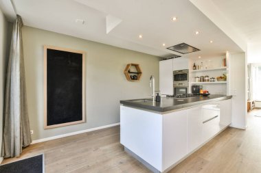 Açık bir düzen, minimalist tasarım, entegre cihazlar ve yaratıcılık ve stil için karatahta bir duvar içeren gösterişli bir modern mutfak..